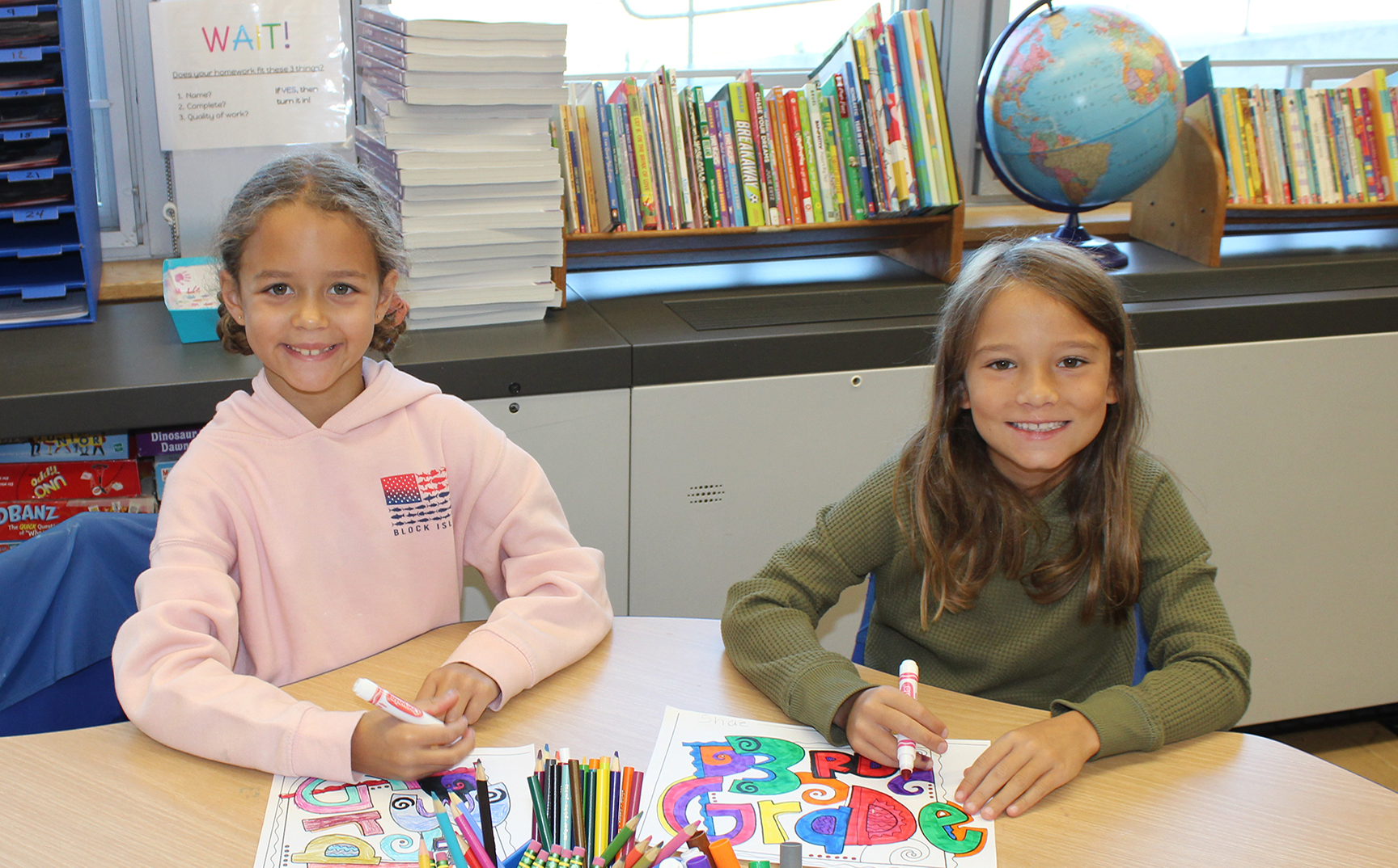 Two students sitting at a table coloring